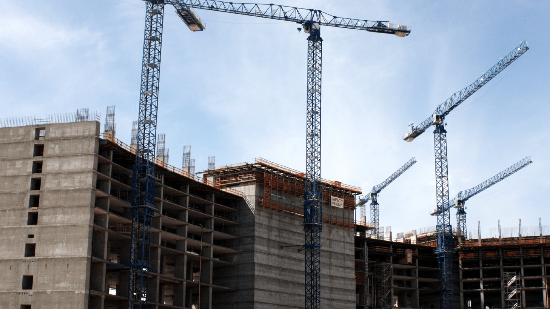 Plac budowy z prętami stalowymi w betonie i żurawie budowlane